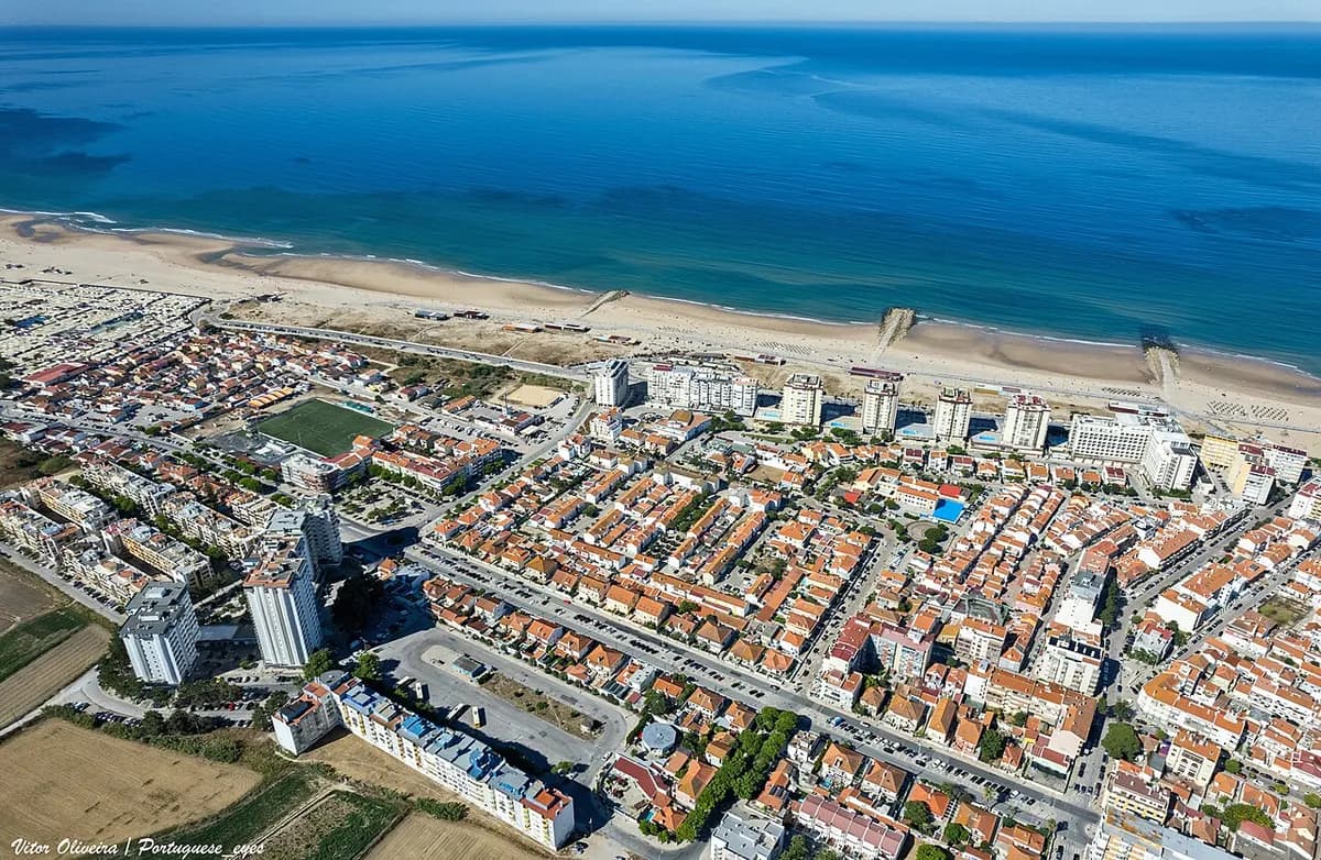 Praia da Cova do Vapor beach with fishing village and Tagus estuary near Lisbon